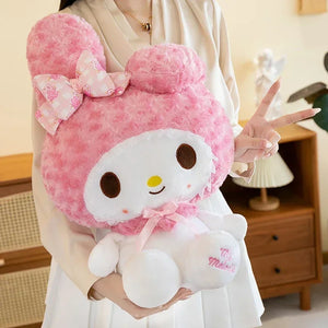 Person holding a large pink plush toy with a bow, indoors.
