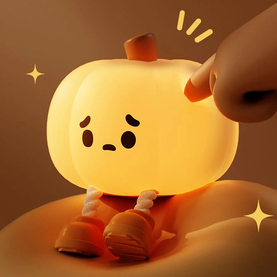 Cute little pumpkin night light glowing softly on a bedside table