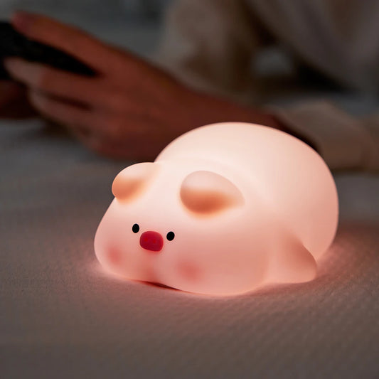 Pink pig night light displayed on a bedside table with a soft glow
