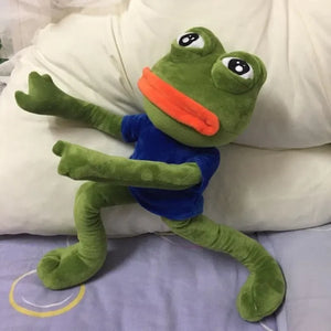 sad frog plush toy laying on a bed with pillow soft stuffed animal for comfort