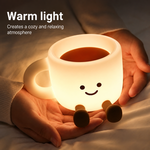 The Cozy Cup Night Light glowing warmly in hands on a bed, creating a cozy and relaxing atmosphere for nighttime comfort